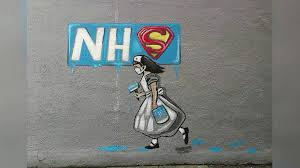Street artwork of a nurse beneath an NHS sign with a superhero emblem.